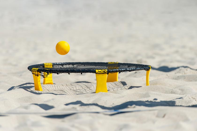 Spikeball Netz mit gelbem Roundnet Ball im sonnigen Sandstrand